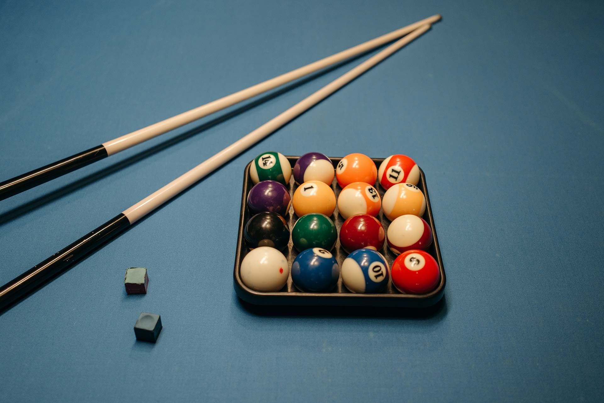 Pool cues, balls and chalk on a pool table